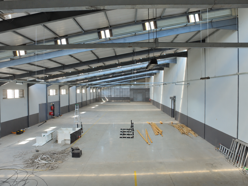 Spacious industrial warehouse featuring high ceilings with exposed steel beams, abundant natural light from skylights, and durable concrete flooring.