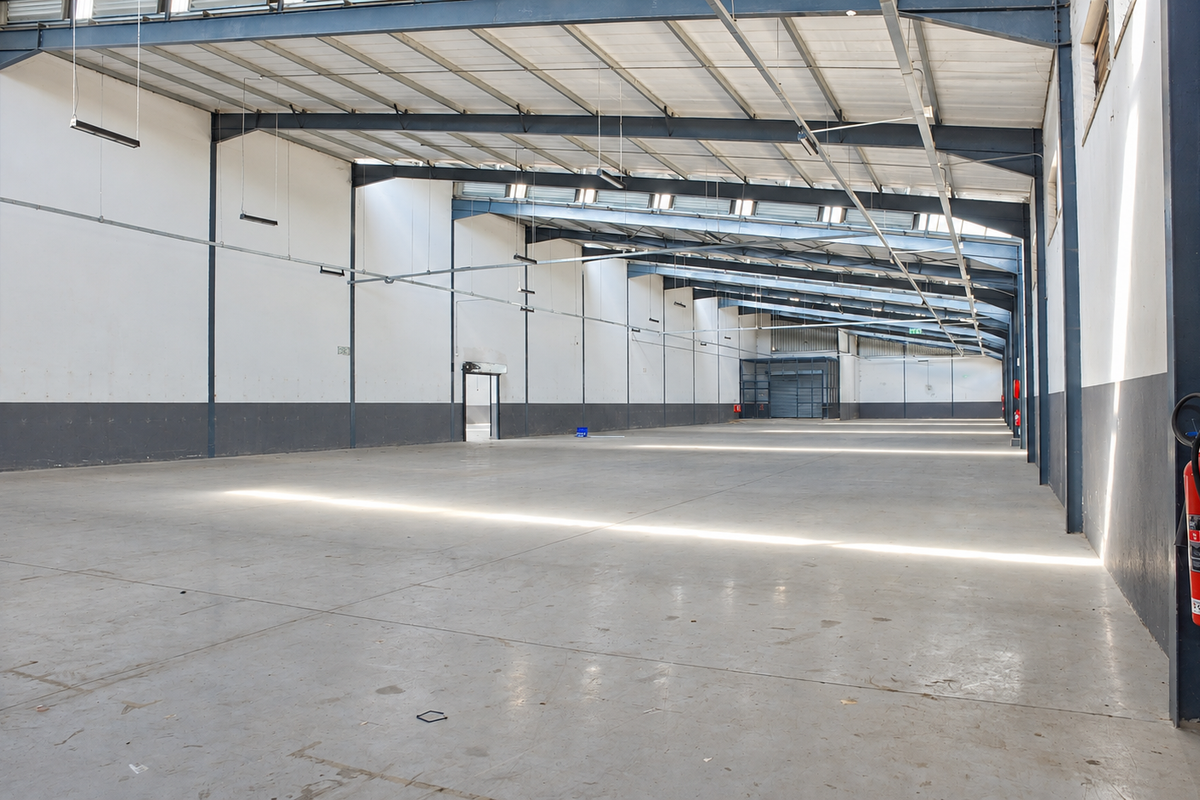 Spacious industrial warehouse featuring high ceilings, exposed steel portal frame, polished concrete flooring, and ample natural light through integrated skylights.