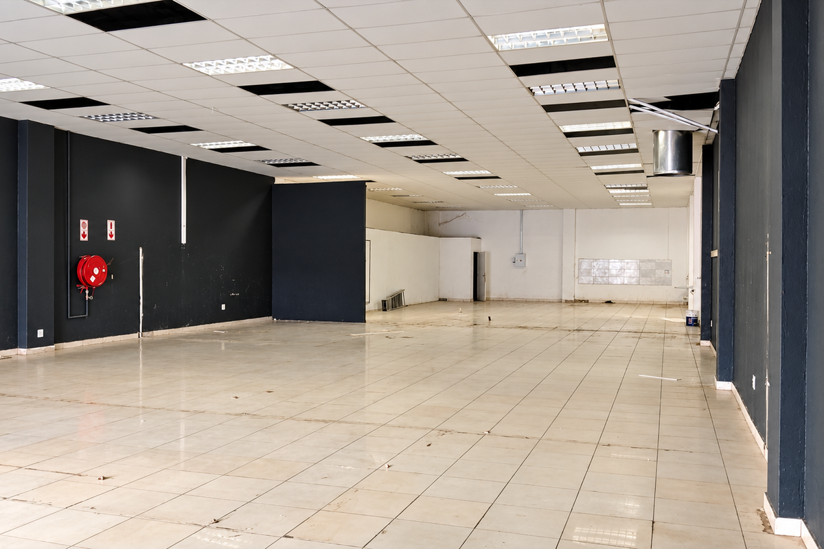 Spacious open-plan retail area featuring tiled flooring, a suspended ceiling with recessed lighting, and a wall-mounted fire hose reel.