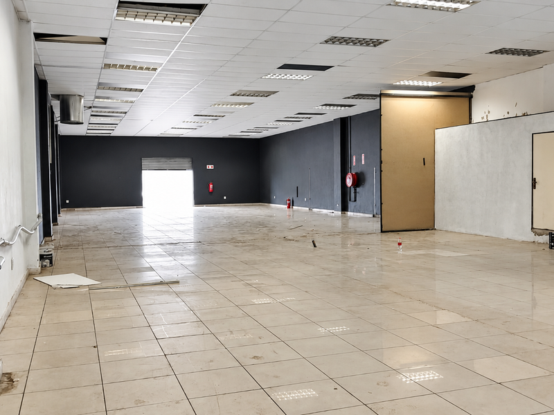 A large, open-plan retail space featuring ceramic tile flooring, a suspended ceiling with recessed lighting, and a neutral color palette ready for customization.