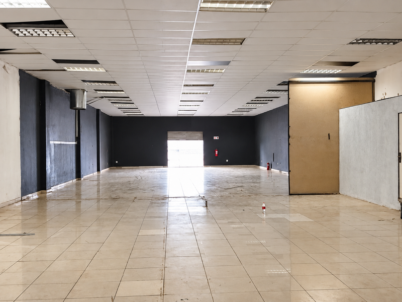 Spacious open-plan retail unit featuring tiled flooring, a suspended ceiling with integrated lighting, and a rear roller shutter door access.