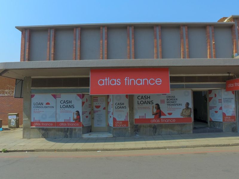 Front elevation of a commercial business premises featuring a brick facade, concrete awning, and large storefront windows with branded signage.