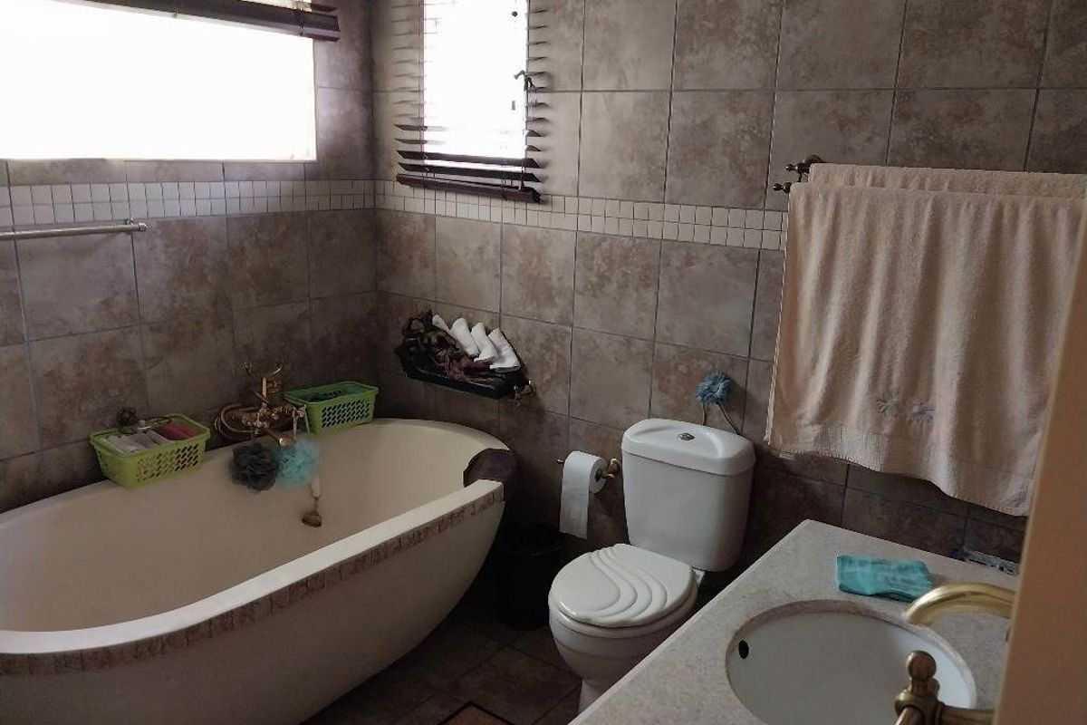 A functional bathroom featuring a freestanding bathtub, built-in vanity with basin, toilet, and neutral ceramic wall and floor tiling.