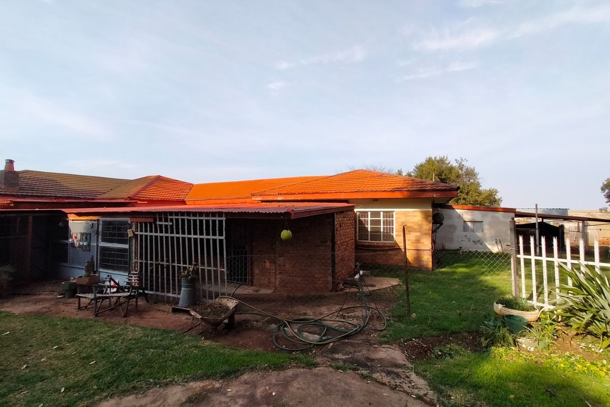 Rear view of the farm property featuring a brick exterior, tiled roof, and a covered patio area with security bars.