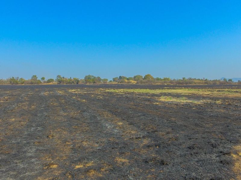 An aerial view of a large, flat commercial vacant land plot showing signs of recent vegetation clearing or fire damage.
