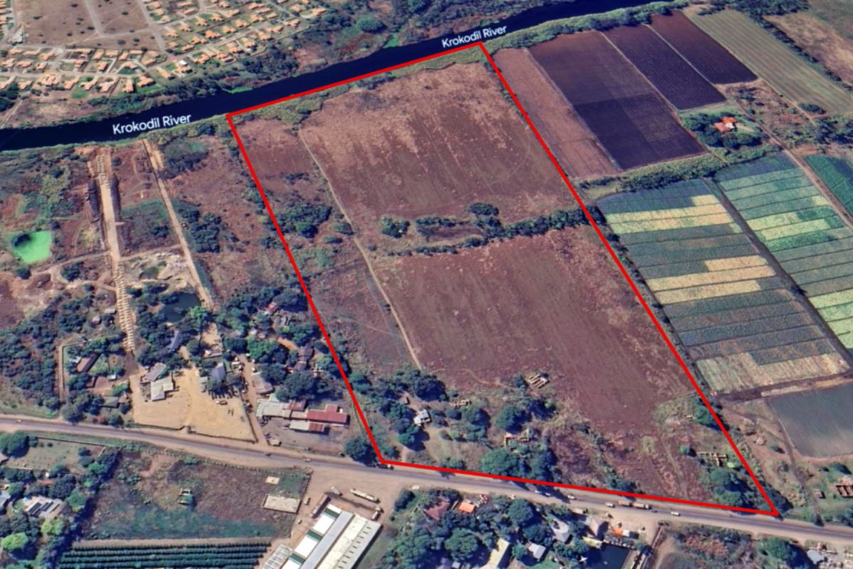 Aerial view of a large commercial vacant land parcel featuring direct river frontage and road access.