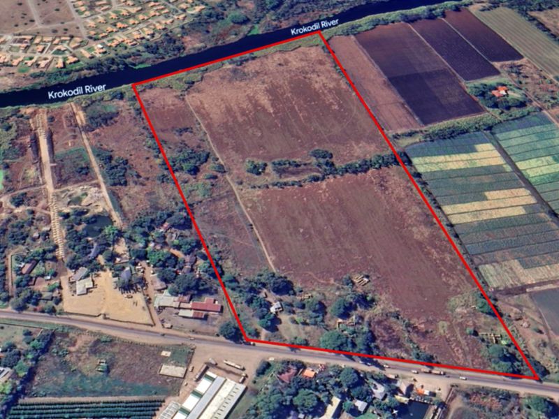 Aerial view of a large commercial vacant land parcel featuring direct river frontage and road access.