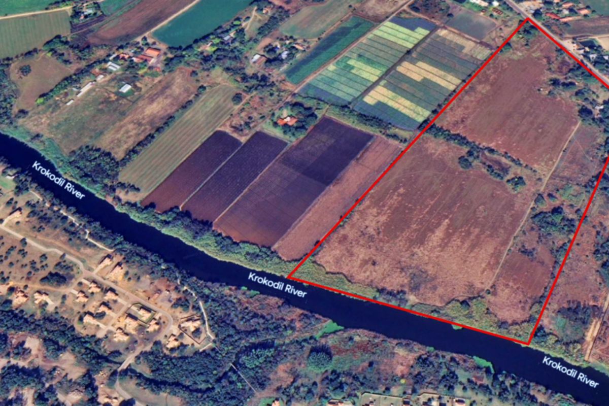 Aerial view of a large vacant commercial land parcel featuring extensive river frontage along the Krokodil River.