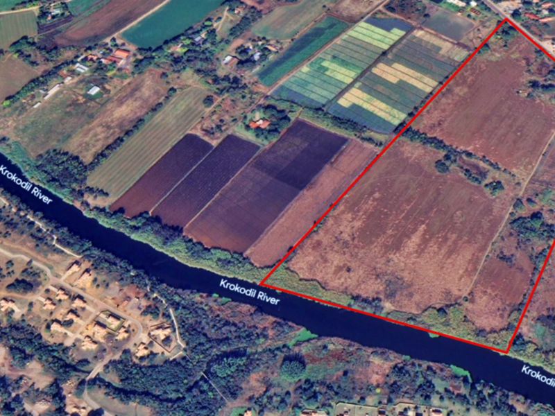 Aerial view of a large vacant commercial land parcel featuring extensive river frontage along the Krokodil River.