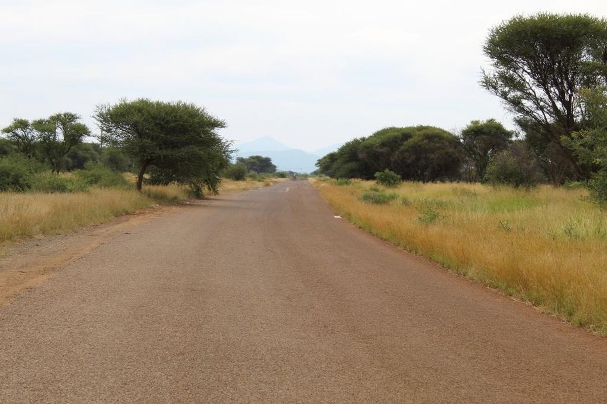 A view of a paved road passing through open grassland and natural vegetation, characteristic of a rural commercial land setting.