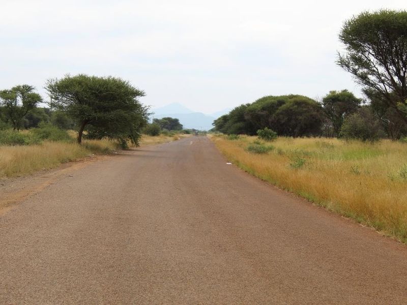 A view of a paved road passing through open grassland and natural vegetation, characteristic of a rural commercial land setting.