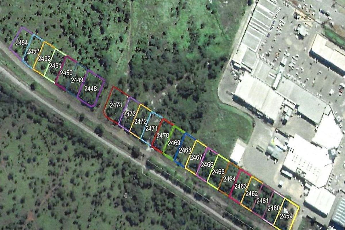 An aerial view showing multiple demarcated commercial land parcels with surrounding vegetation and nearby infrastructure.