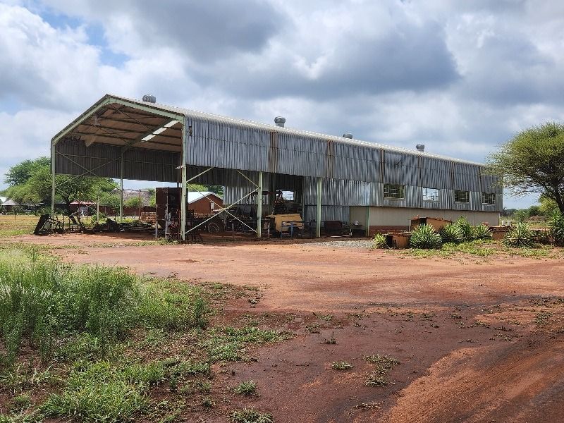 Large open-sided agricultural shed with corrugated metal cladding and steel frame construction, suitable for farm equipment storage or utility purposes.