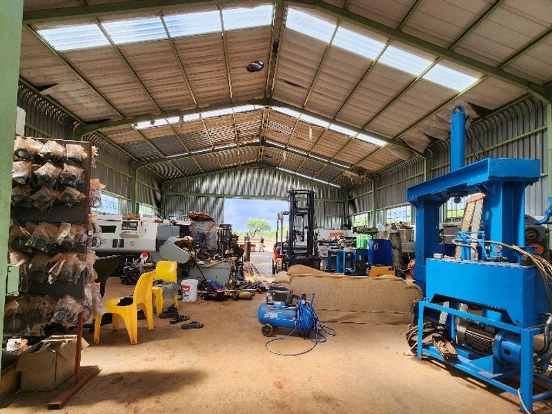 Large industrial utility shed featuring a steel frame structure, corrugated metal roofing with translucent panels, and a concrete floor, suitable for workshop or storage use.