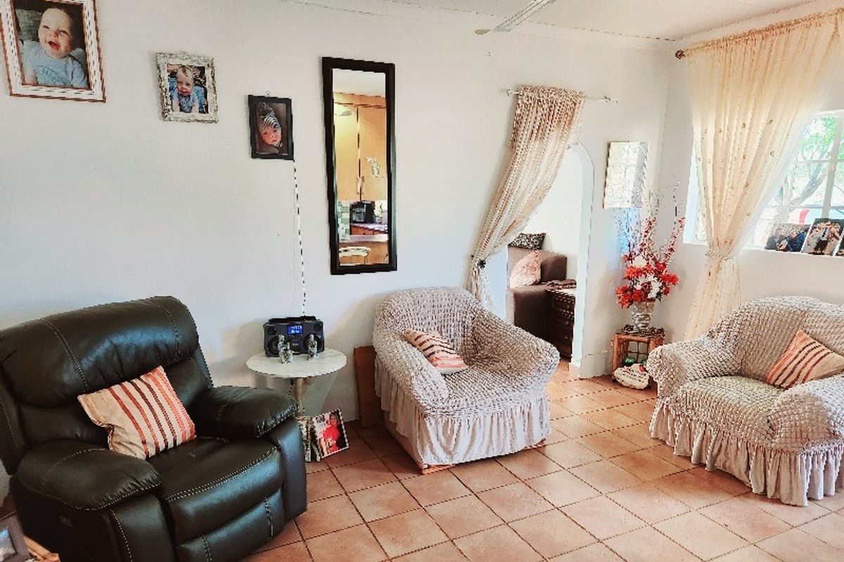A living room featuring tiled flooring, an arched doorway leading to an adjacent space, and a ceiling fan.