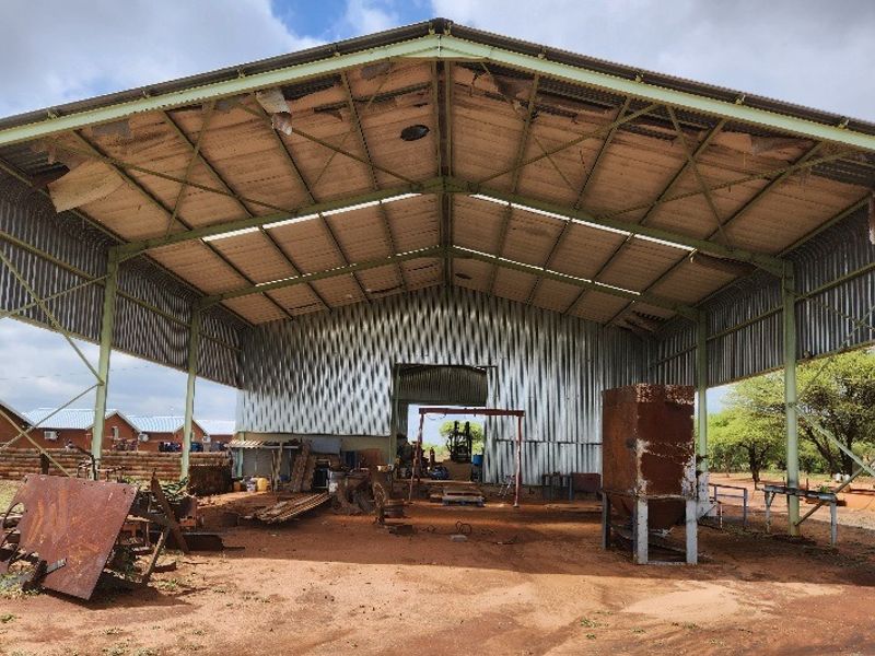 Large open-sided agricultural utility shed featuring a steel frame and corrugated metal roofing, suitable for storage or farm equipment maintenance.