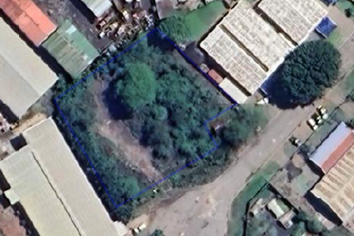 Aerial view of a vacant commercial land plot surrounded by industrial buildings and warehouses.