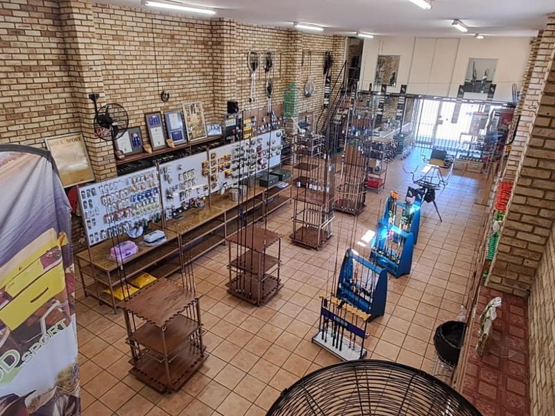 Spacious retail interior featuring exposed brick walls, ceramic tile flooring, and overhead fluorescent lighting, currently configured as a sports equipment store.