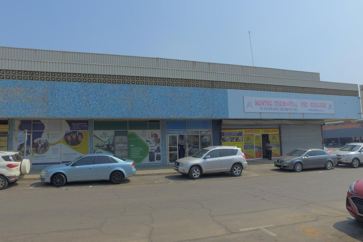 Front elevation of a commercial retail building featuring aluminum storefronts, metal roller shutters, and a decorative mosaic tile facade.