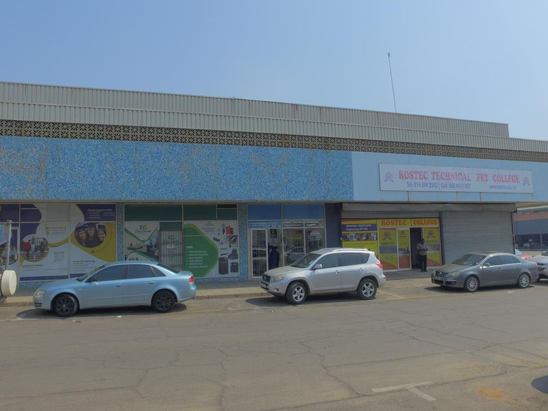Front elevation of a commercial retail building featuring aluminum storefronts, metal roller shutters, and a decorative mosaic tile facade.