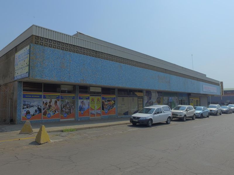 Front elevation of a commercial retail building featuring a blue mosaic tile facade, large storefront windows, and decorative breeze block detailing.