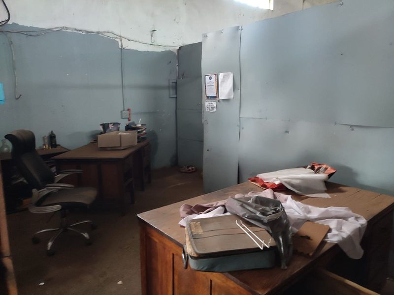 A basic industrial office space featuring partition walls and exposed electrical wiring, requiring significant maintenance and cosmetic updates.