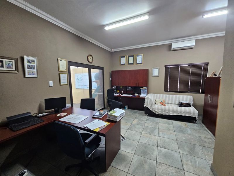 A functional office space featuring tiled flooring, built-in cabinetry, and a wall-mounted air conditioning unit, providing a professional work environment.