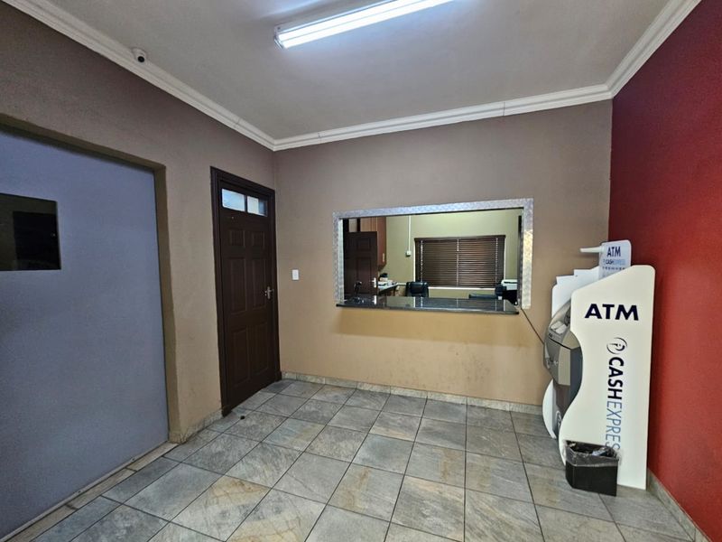 A functional office reception area featuring tiled flooring, a service window, and integrated security infrastructure.