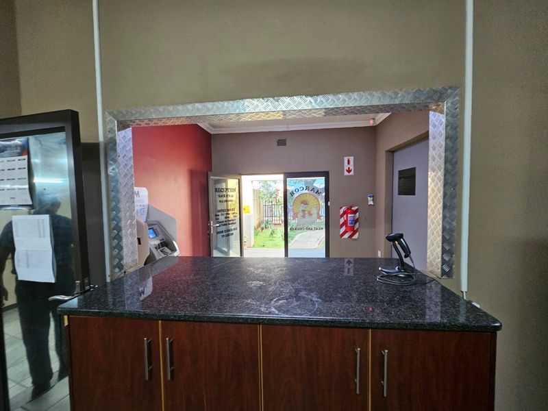A functional reception area featuring a granite-topped service counter with metal trim, providing a clear view through to the main entrance and exterior.