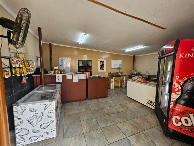 A functional commercial kitchen or service area featuring tiled flooring, a built-in service counter, and basic utility lighting.
