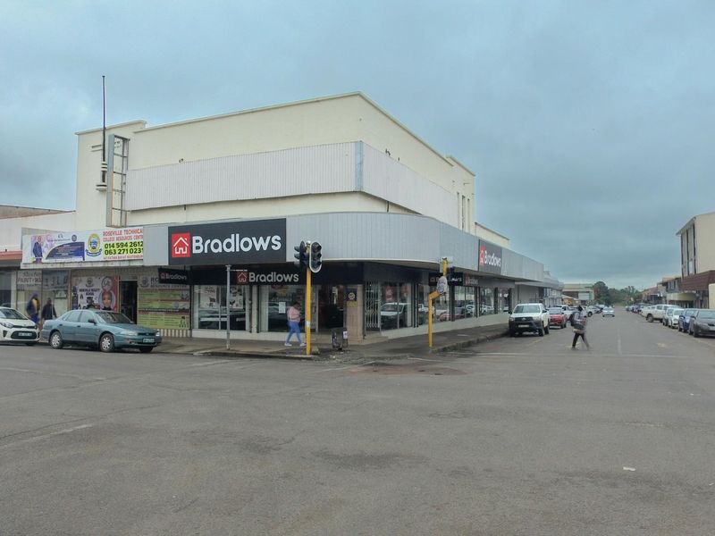 Street-level view of a corner retail property featuring large display windows and prominent signage in a busy commercial area.