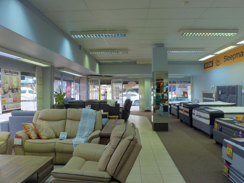 Spacious retail showroom featuring large display windows, a mix of tiled and carpeted flooring, and integrated fluorescent lighting throughout the open-plan space.