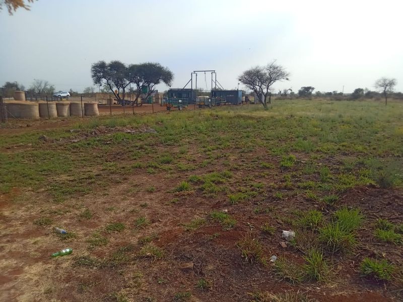 A view of the vacant commercial land featuring wire fencing and existing borehole infrastructure on the property.
