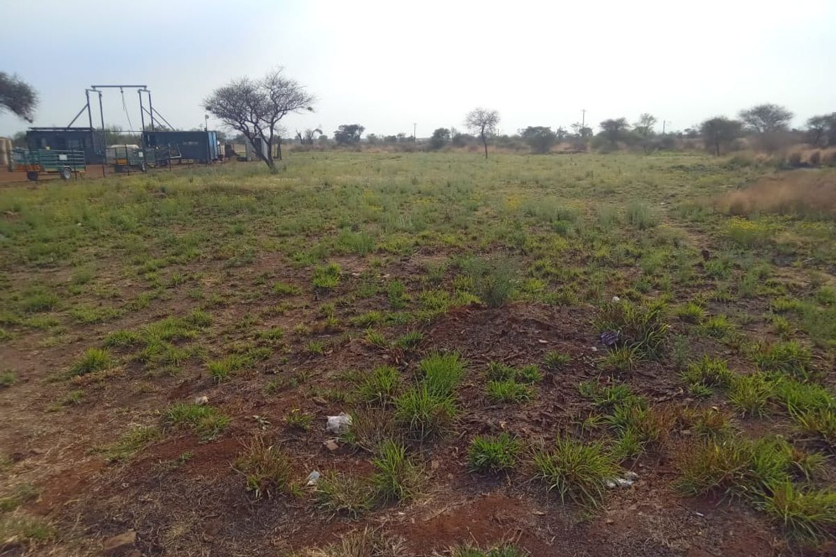 A view of the vacant commercial land featuring open terrain with native vegetation and scattered trees.