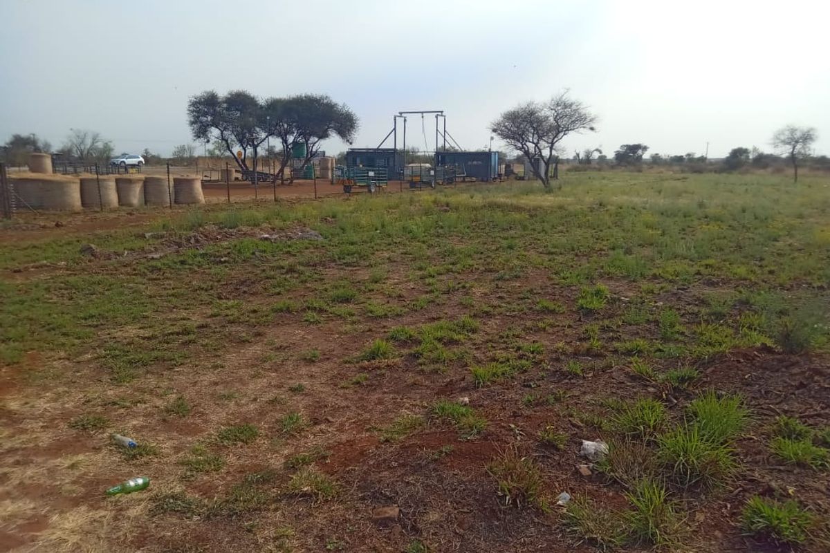 A view of the vacant commercial land featuring wire fencing and existing borehole infrastructure on the property.