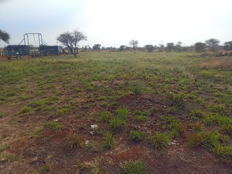 A view of the vacant commercial land featuring open terrain with native vegetation and scattered trees.