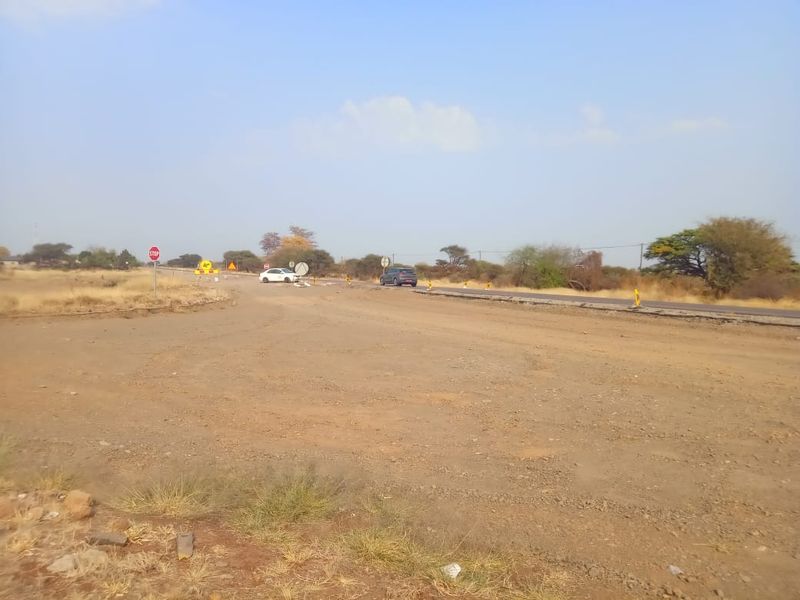 A view of the unpaved access area adjacent to a public asphalt road with visible road signage.