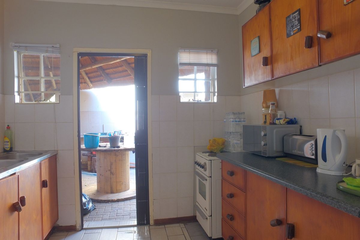 A functional kitchen featuring wooden cabinetry, tiled backsplash, and a freestanding stove, with direct access to an outdoor patio area.