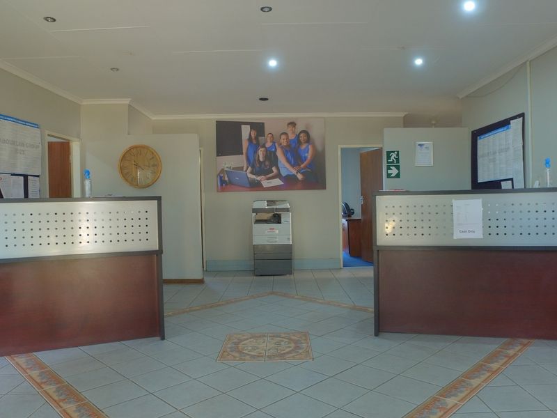 A professional office reception area featuring dual reception desks, tiled flooring, and recessed lighting, providing a functional workspace for client arrivals.