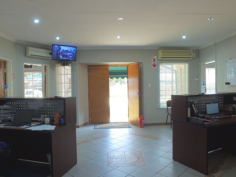 A functional office space featuring ceramic tiled flooring, recessed lighting, and dual split-system air conditioning units, providing a practical work environment.
