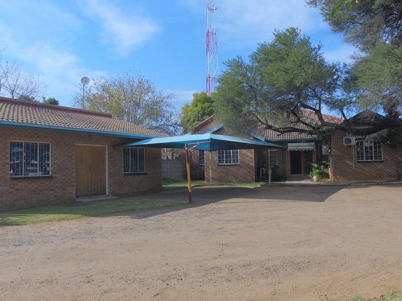 Exterior view of a brick office building featuring a shaded parking area and established trees on the property grounds.