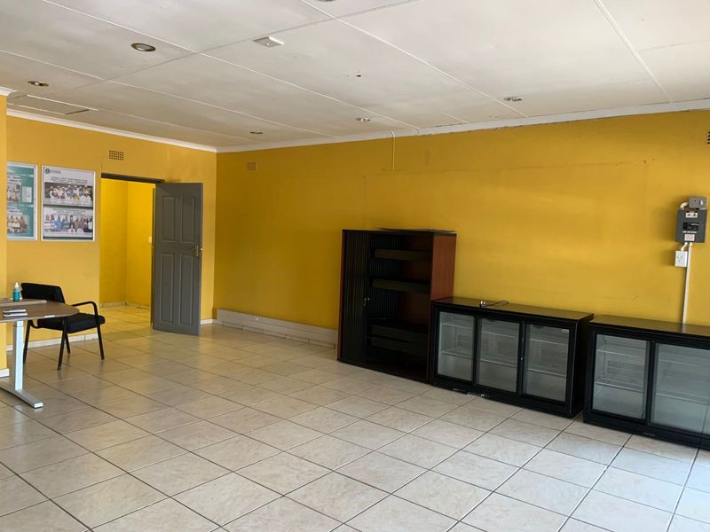A functional office space featuring tiled flooring, recessed lighting, and yellow painted walls, suitable for a professional workspace or commercial use.