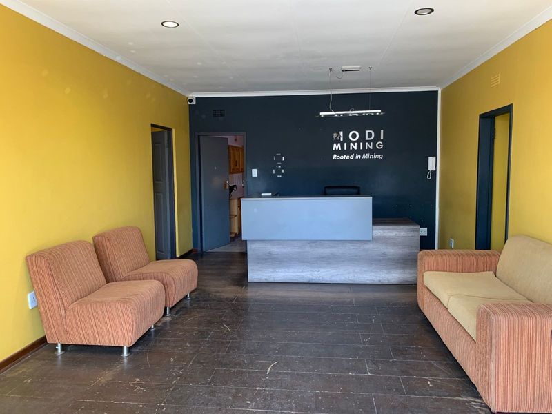 Office reception area featuring a built-in desk, tiled flooring, and recessed lighting, providing a functional space for client arrivals.