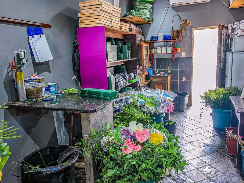 A functional utility and workspace area featuring tiled flooring, a built-in sink, and wall-mounted shelving, suitable for various commercial or storage purposes.
