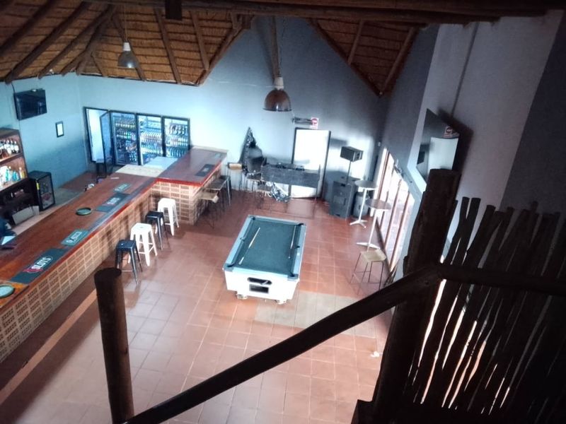 Spacious bar area featuring a built-in counter, high thatch ceilings with exposed timber rafters, and tiled flooring, suitable for entertainment and social gatherings.