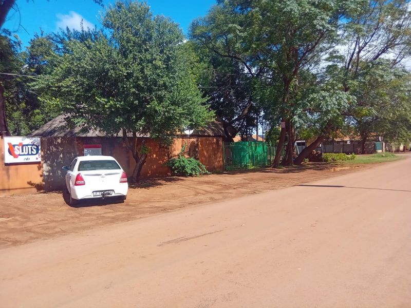Street view of the property entrance featuring a perimeter wall, metal gate, and mature trees.