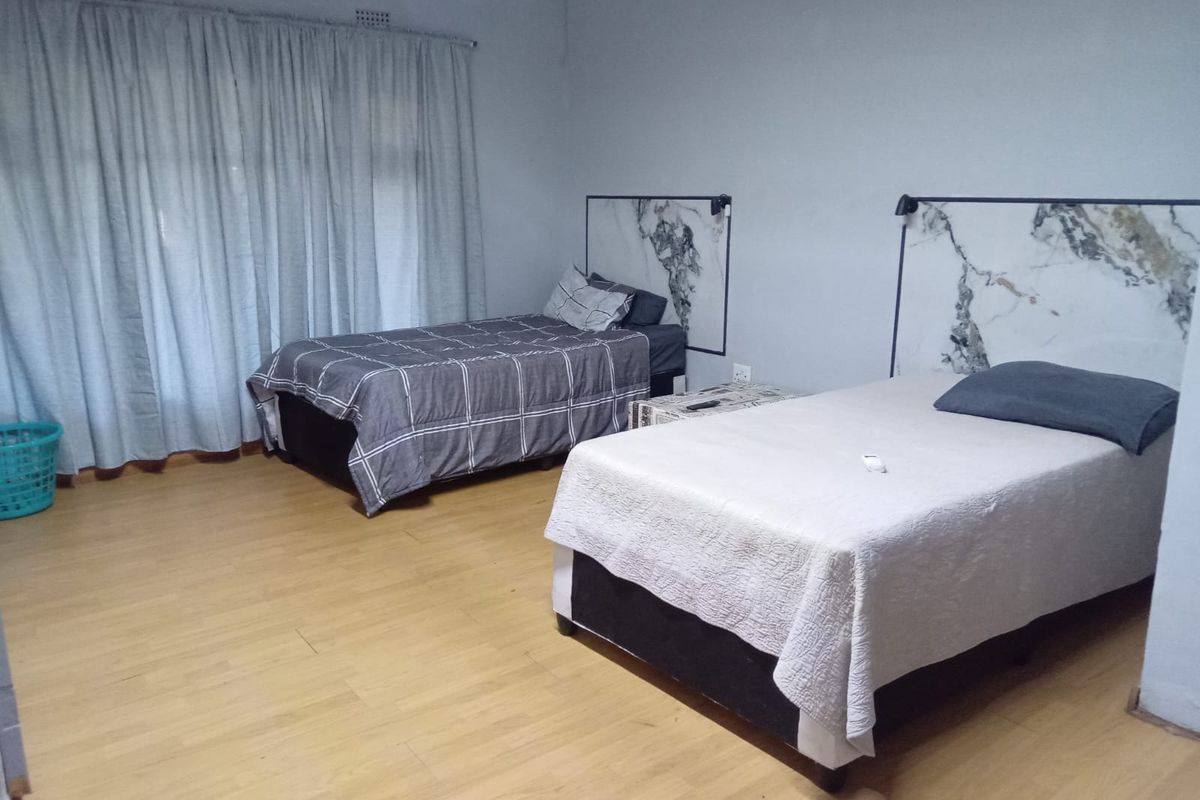 A bedroom featuring laminate flooring and custom built-in marble-effect headboards, providing a functional space for guests.
