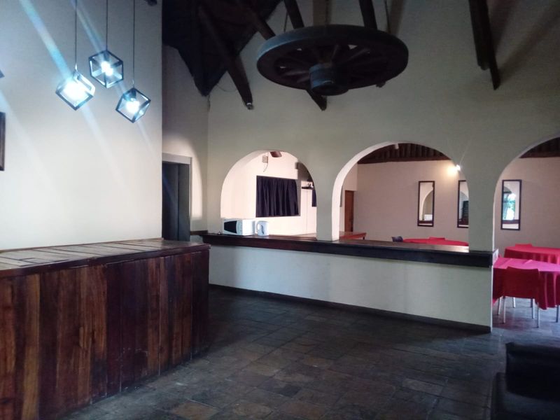 A rustic bar area featuring a built-in wooden counter, stone flooring, and distinctive arched architectural details with exposed timber beams.