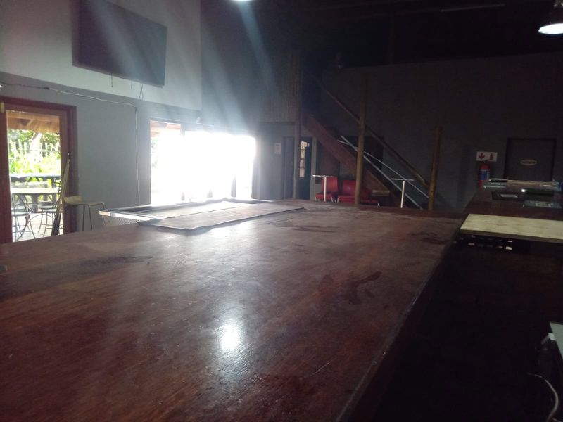 A rustic bar area featuring a large wooden counter, staircase, and direct access to an outdoor patio area.