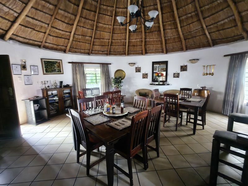Spacious dining area featuring a traditional thatched roof with exposed timber rafters and ceramic tiled flooring, creating a rustic farm-style atmosphere.